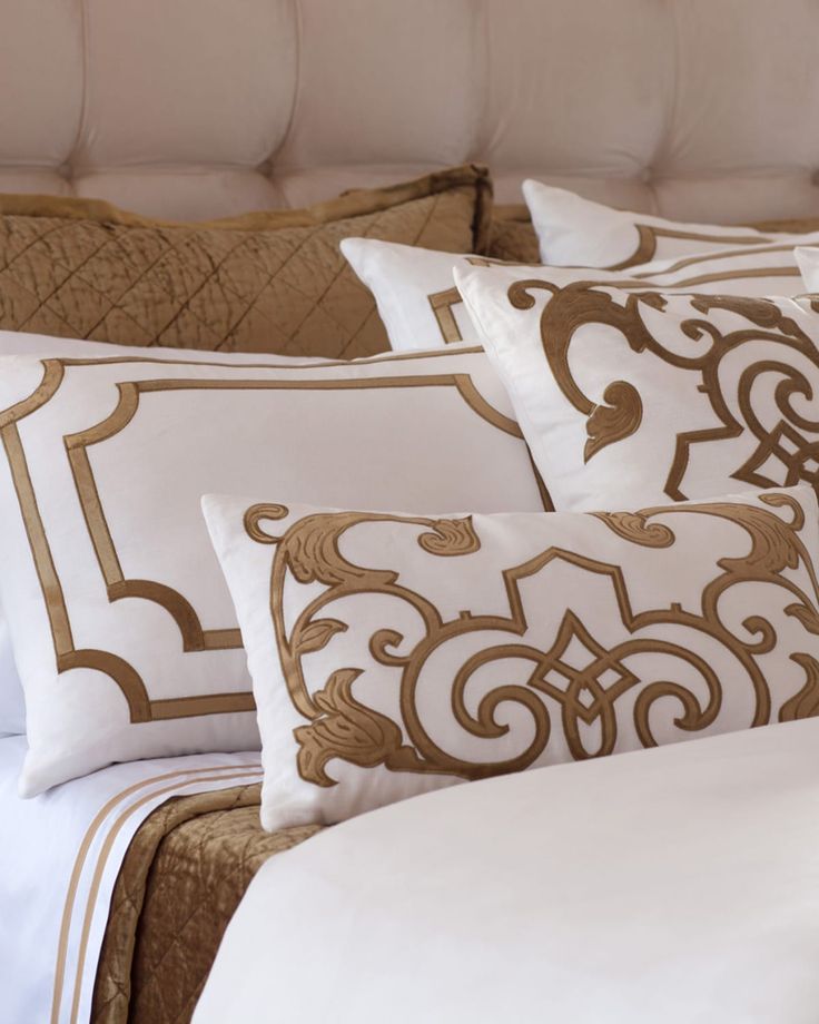 a bed with white and gold pillows on it