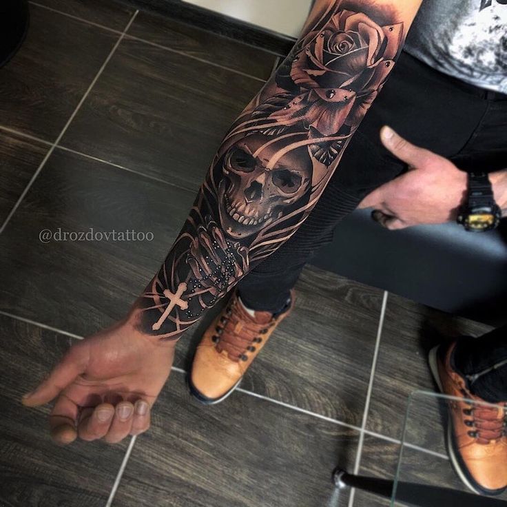 a man's arm with a skull and rose tattoo on it