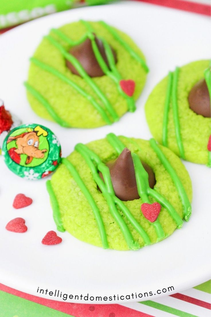 green cookies with chocolate drizzled on top and candy candies around the edges