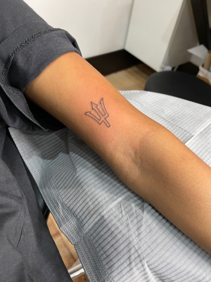 a person sitting in a chair with a tattoo on their arm that has an arrow