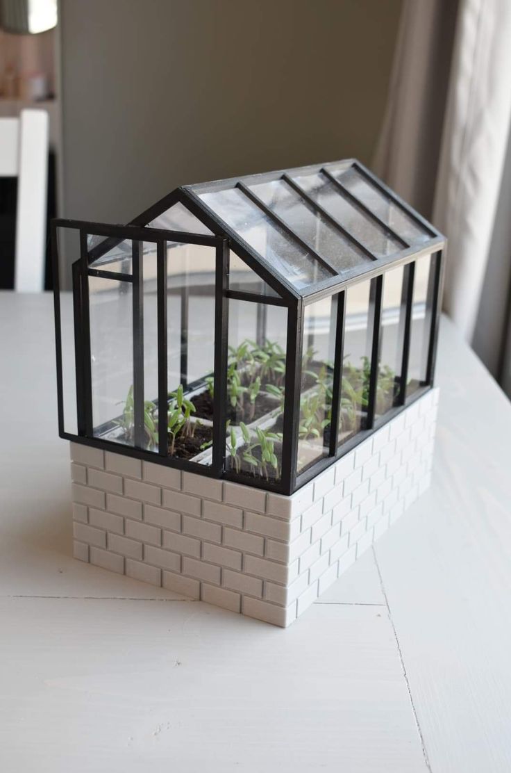 a miniature house made out of bricks with plants inside