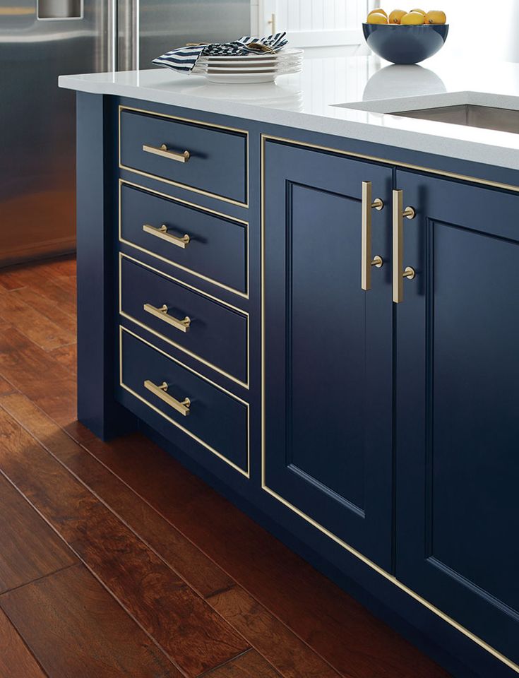 a kitchen with blue cabinets and white counter tops, gold trim on the doors and drawers