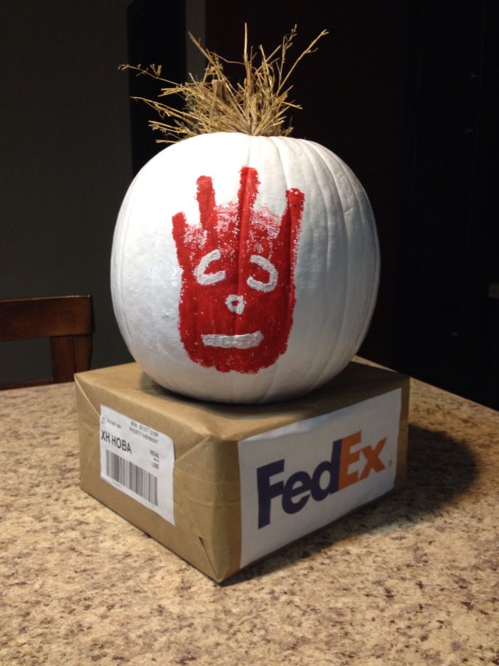 a white pumpkin with a hand print on it sitting on top of a fedex box