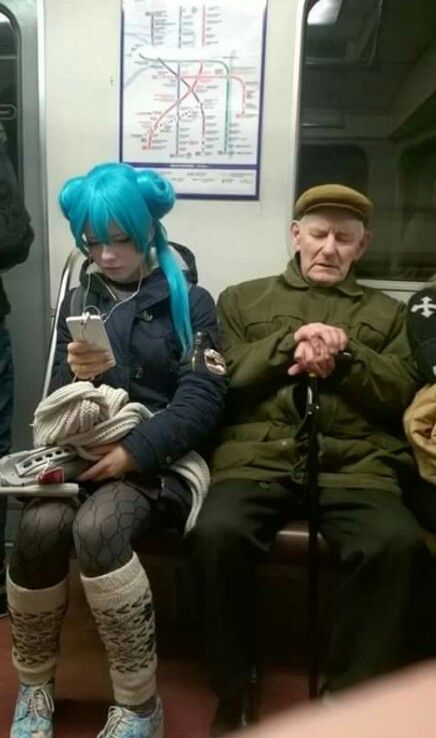 two people sitting on a subway train next to each other, one with blue hair