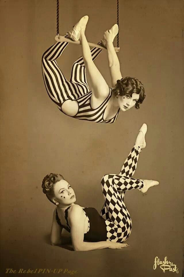 two women are hanging upside down in the air, one is wearing a checkered dress