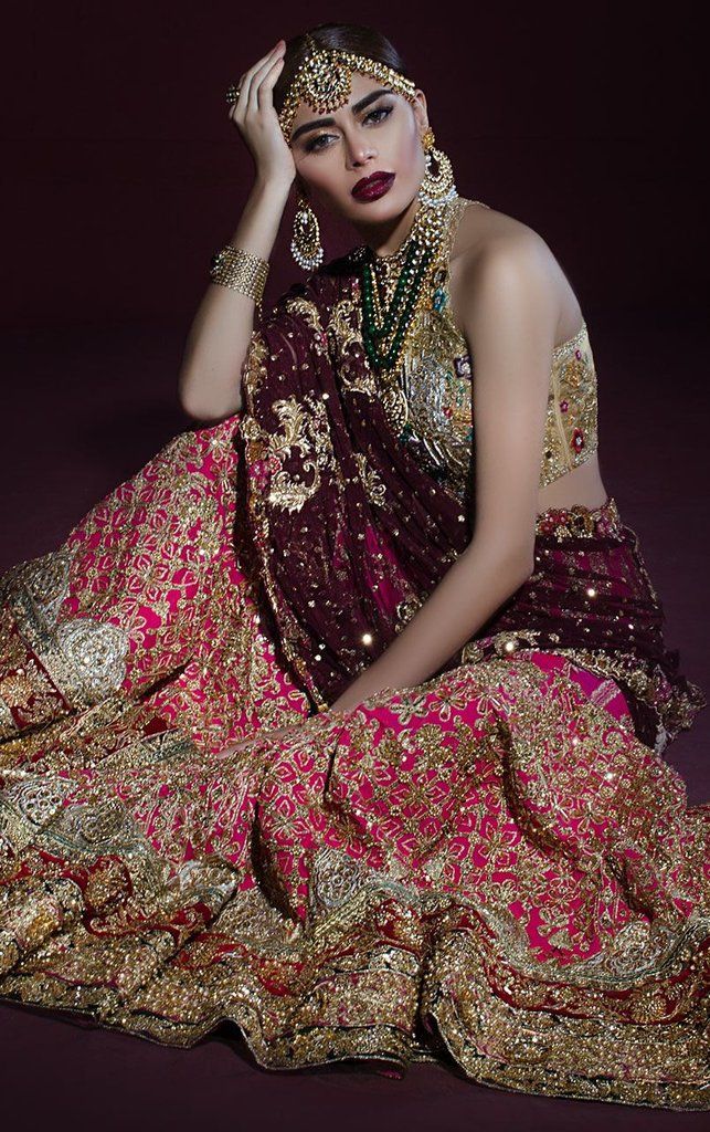 a woman in a red and gold dress sitting on the ground with her hands behind her head