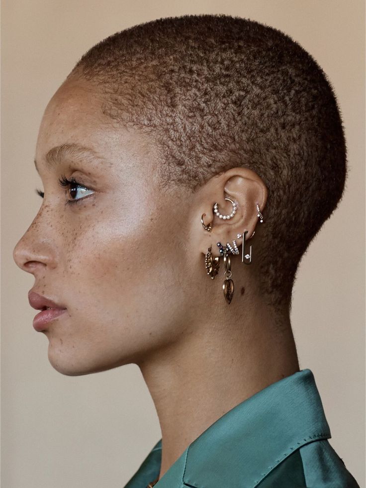 a black and white photo of a woman with short hair wearing earrings on her ear