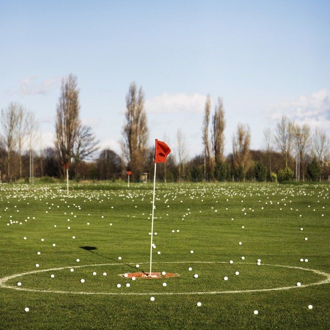 a green field with white balls and a red flag