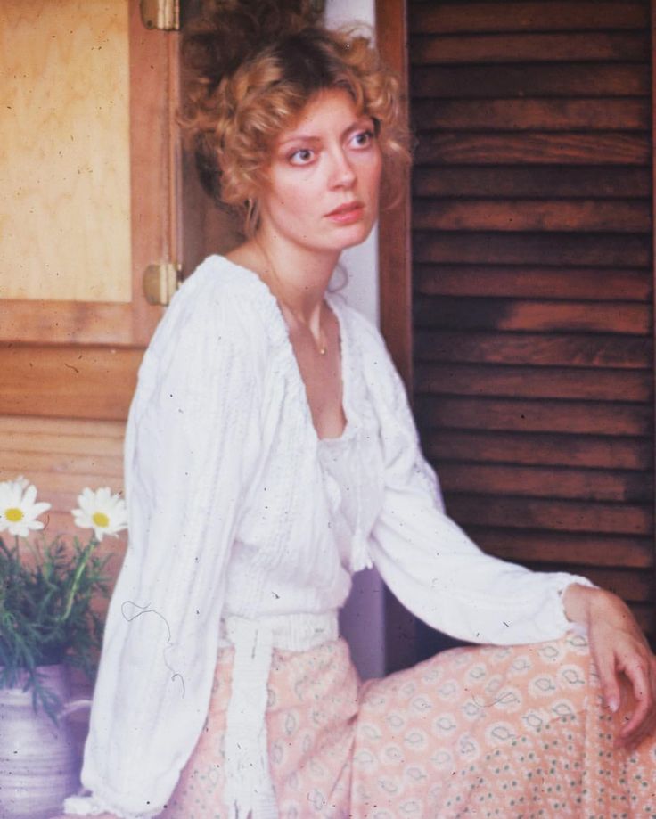 a woman sitting on the floor in front of some flowers