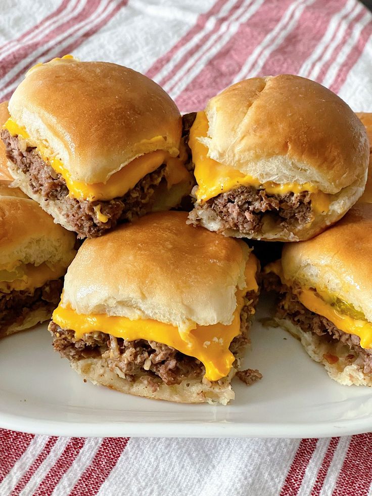 several hamburgers stacked on top of each other on a white plate with red and white cloth