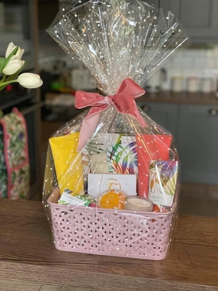 a basket filled with lots of items on top of a wooden table next to a vase