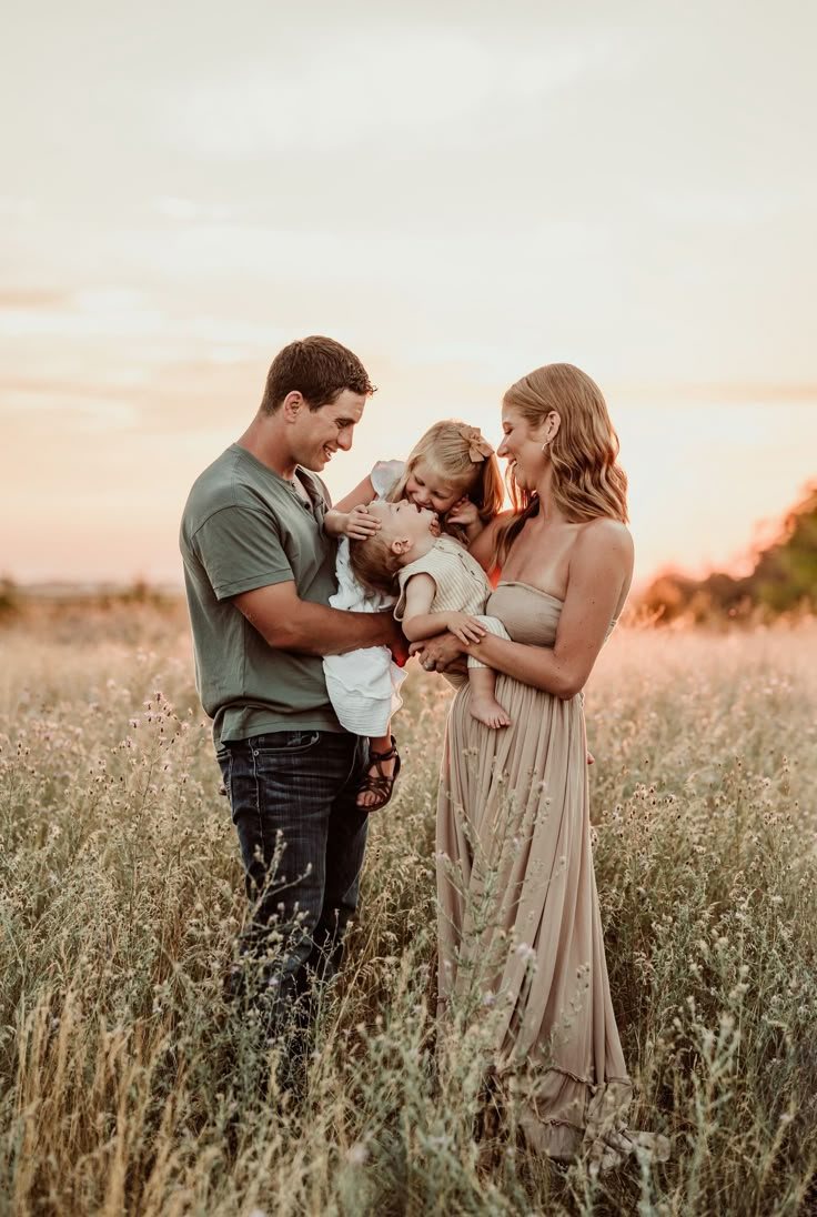 a family standing in tall grass at sunset