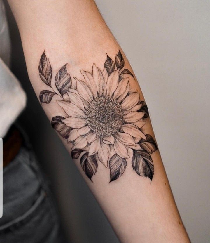 a woman's arm with a sunflower tattoo on it