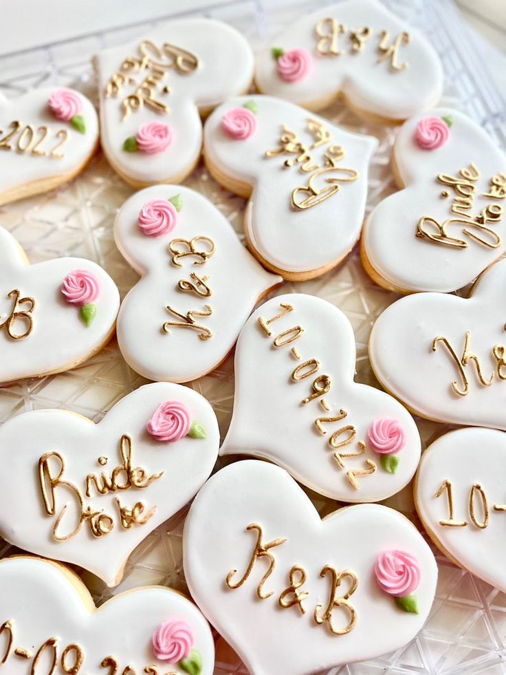 decorated cookies in the shape of hearts with names and date written on them, sitting on a glass platter