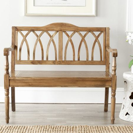 a wooden bench sitting on top of a rug next to a white vase and plant