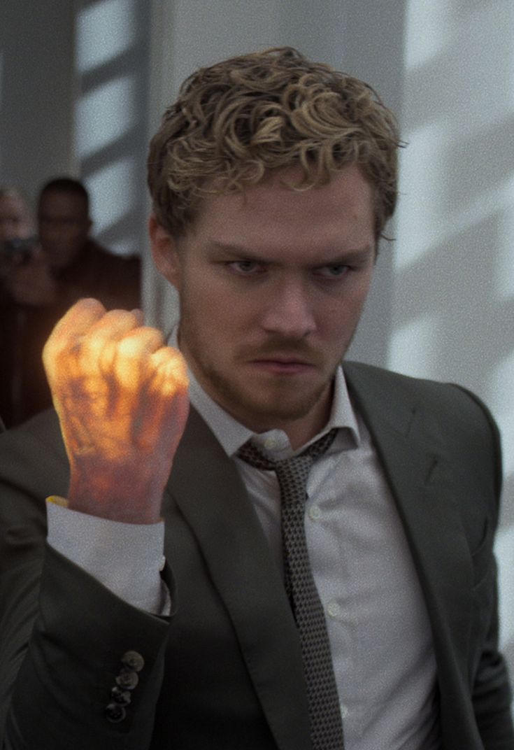 a man in a suit and tie holding his hand up