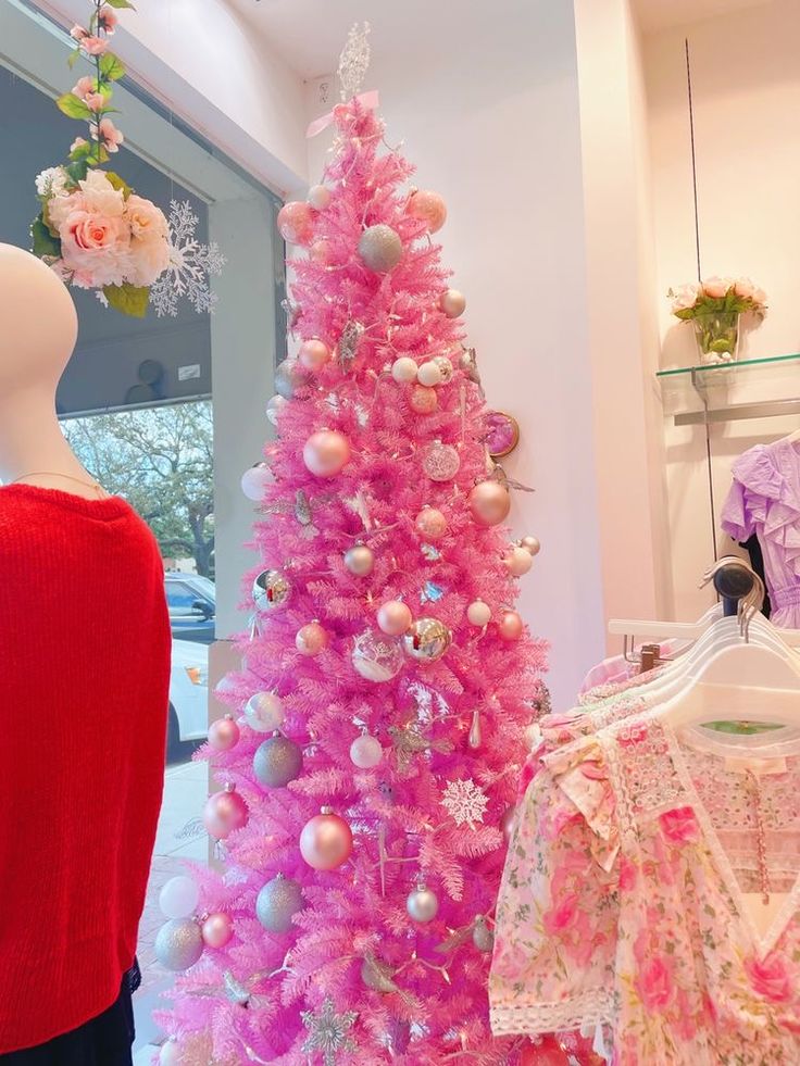 a pink christmas tree next to a mannequin