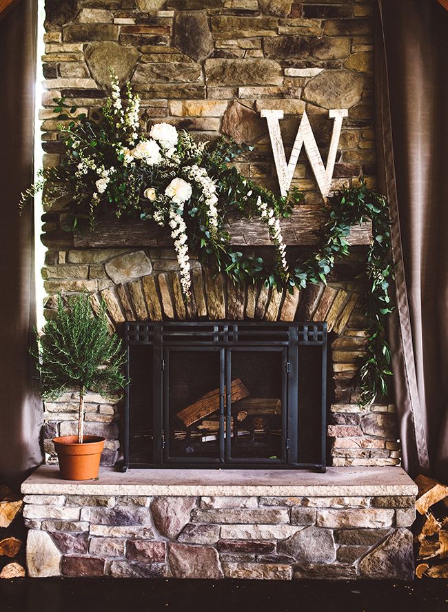 the fireplace is decorated with flowers and greenery