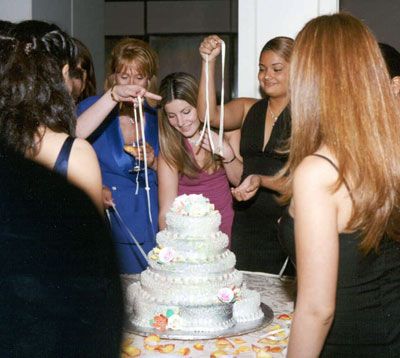 a group of women standing around a white cake