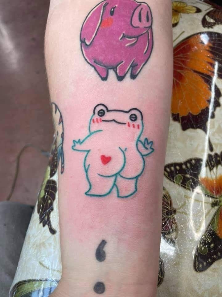 a person with a tattoo on their arm has a pig, frog and butterfly design