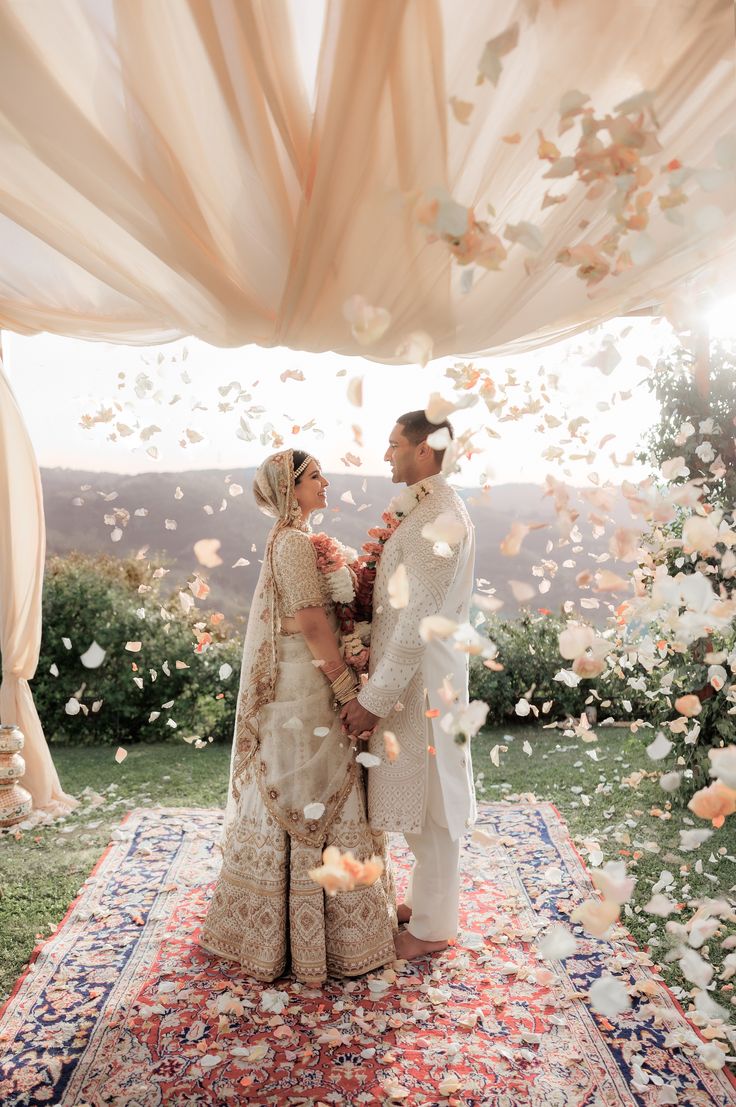 two people standing under a canopy covered in petals