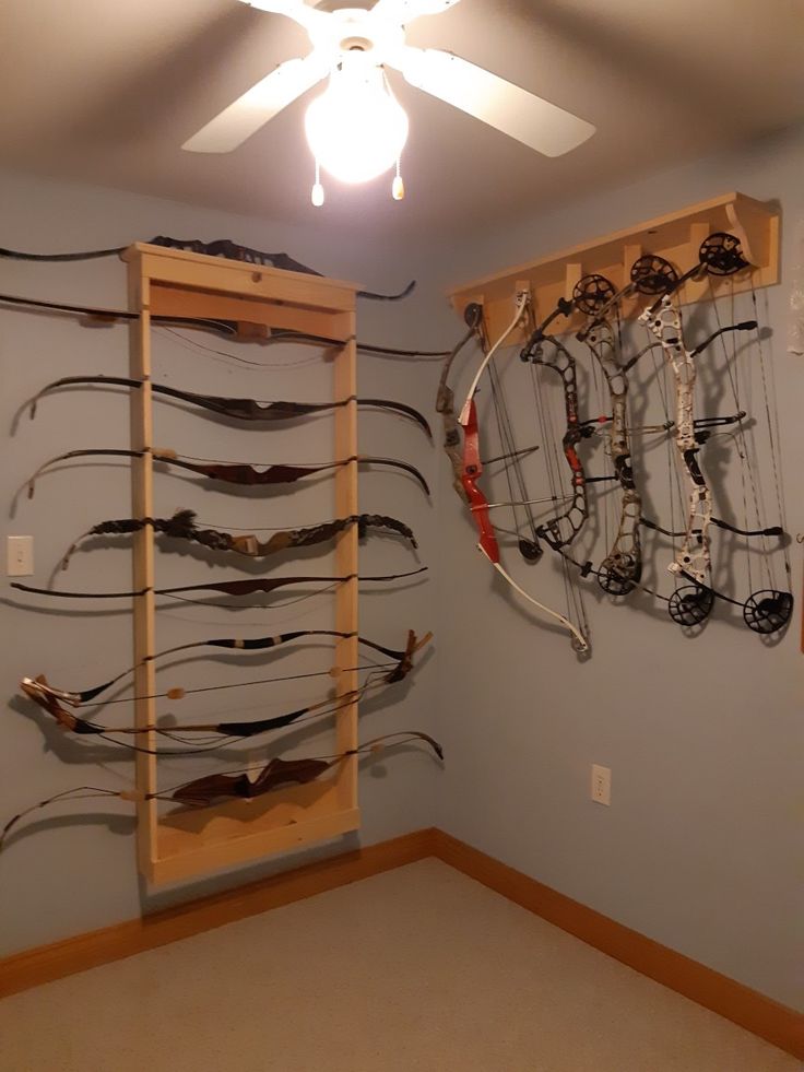 a room filled with lots of different types of bow bows and arrows on shelves next to a ceiling fan