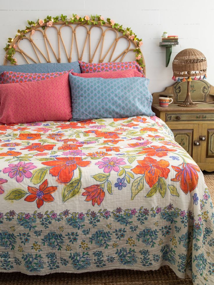 a bed with colorful pillows on top of it and a wicker headboard in the background