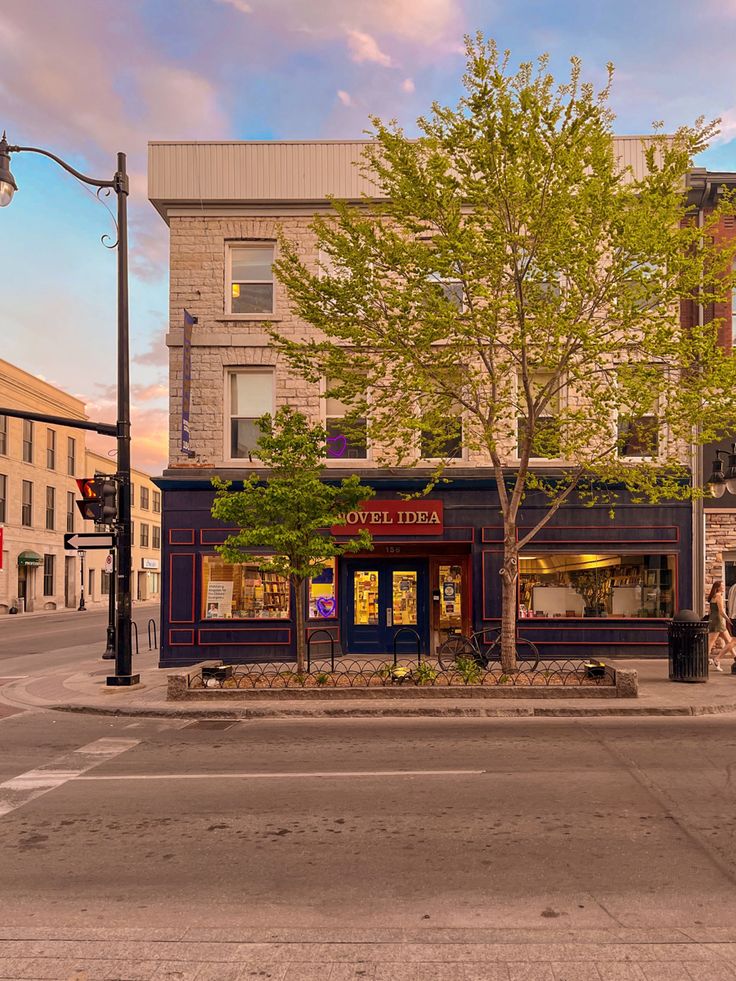 an empty street corner with a store on the corner and trees in front of it