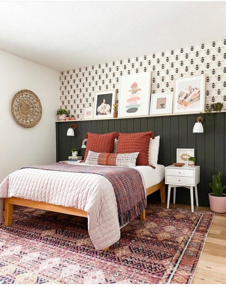 a bed sitting on top of a wooden floor next to a wall with pictures above it