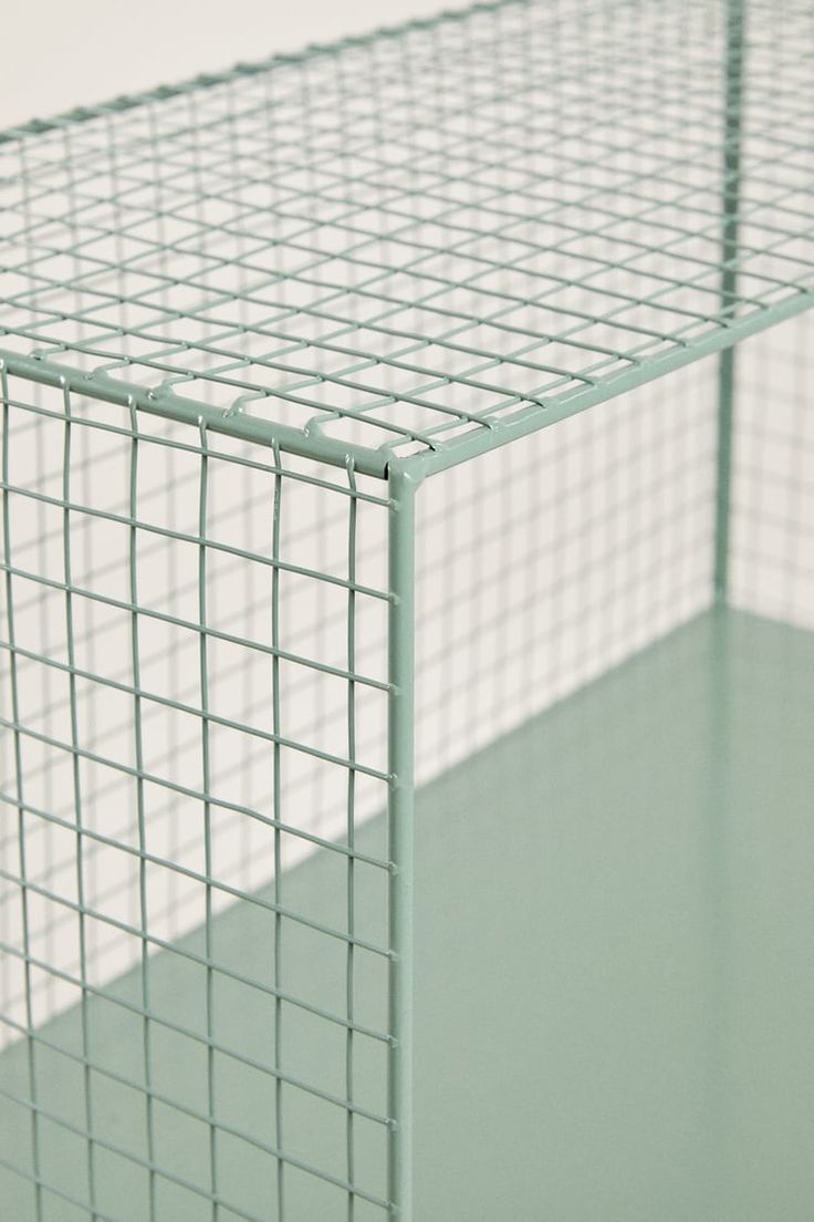 a close up view of a green metal cage on a white surface with no people in it