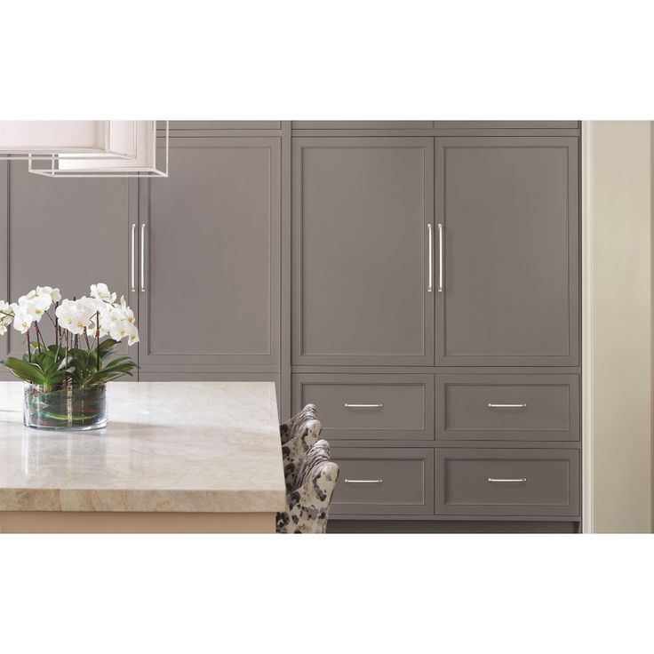 a kitchen with gray cabinets and white flowers in a vase on the counter top next to an oven