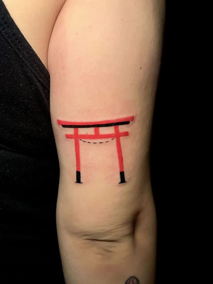 a woman's arm with a tattoo on it that has the letter t in red