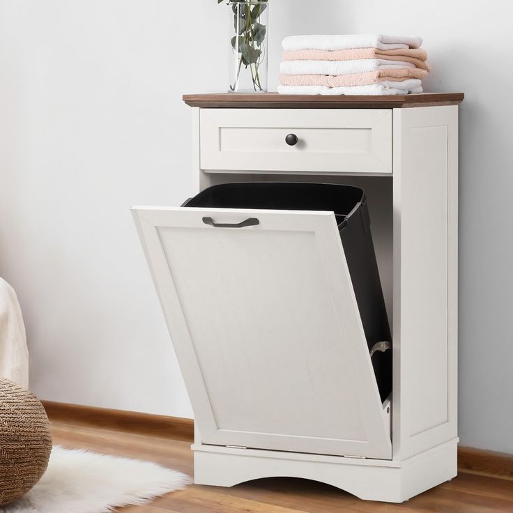 a white cabinet that has some towels on it and a vase with flowers in it