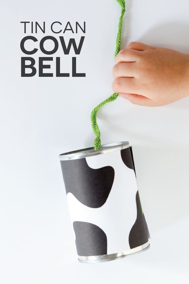 a hand holding a green string attached to a cow print can with the words tin can cow bell on it