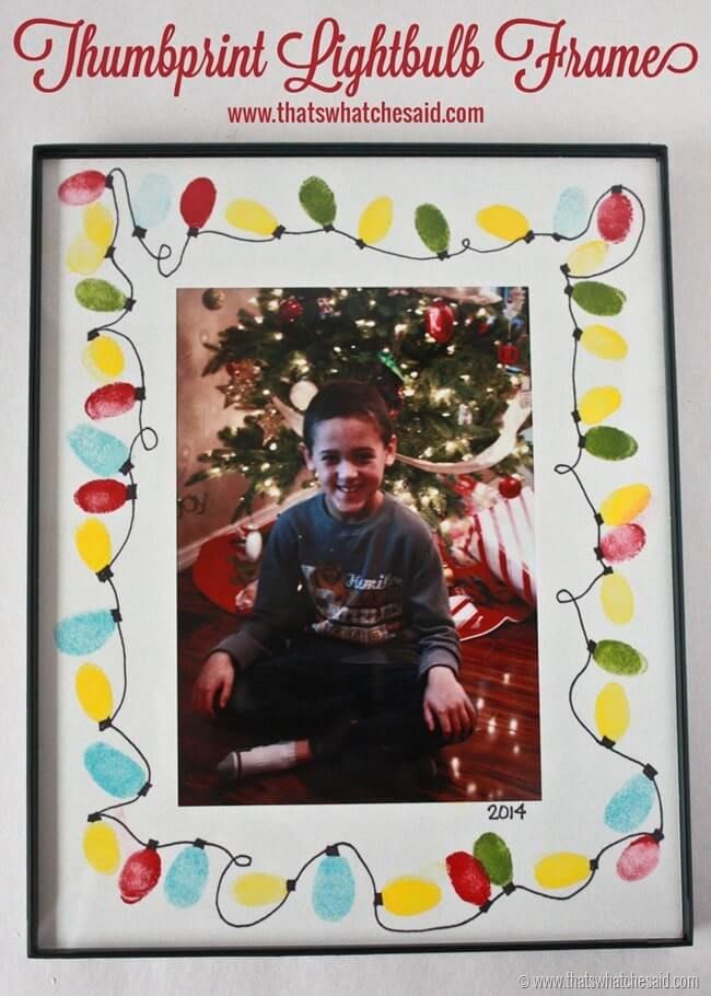 a young boy sitting in front of a christmas tree with lights on it's frame