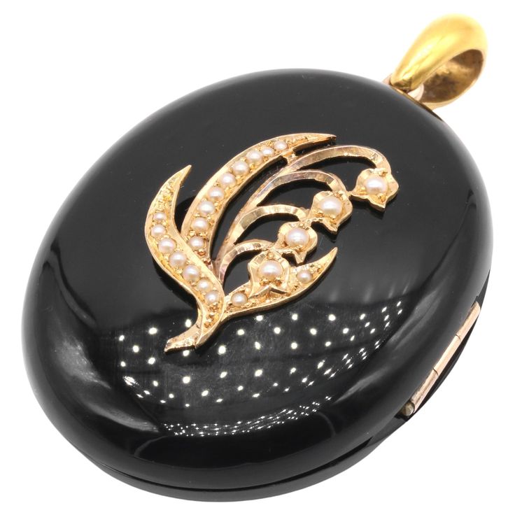 A Victorian yellow gold, black paste, and seed pearl locket, comprising two oval cabochons of black paste, twenty-two seed pearls, set in 9 karat yellow gold, with an 18 karat yellow gold bale. This symbolic Victorian mourning locket is comprised with two oval cabochons of black paste (glass), which have been highly polished to give the most tactile, pebble-like look and feel. The front of the locket is adorned with seed-pearl set lily of the valley motif. Lily of the valley is a flower rife wit Pearl Locket, Victorian Gold, Pearl Set, Seed Pearl, Pure Gold, Pearl Size, Lily Of The Valley, Oval Cabochon, The Valley