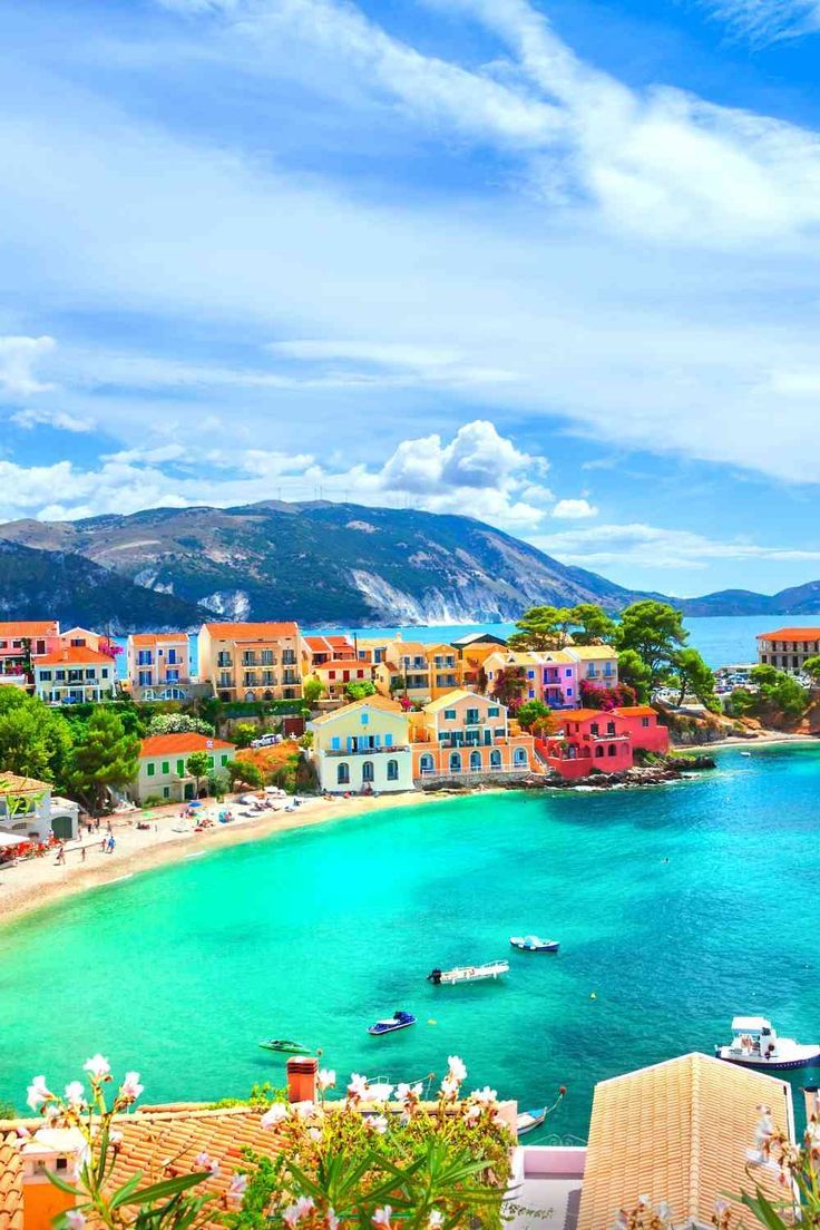 the beach is surrounded by colorful buildings and blue water with boats floating on it's shore