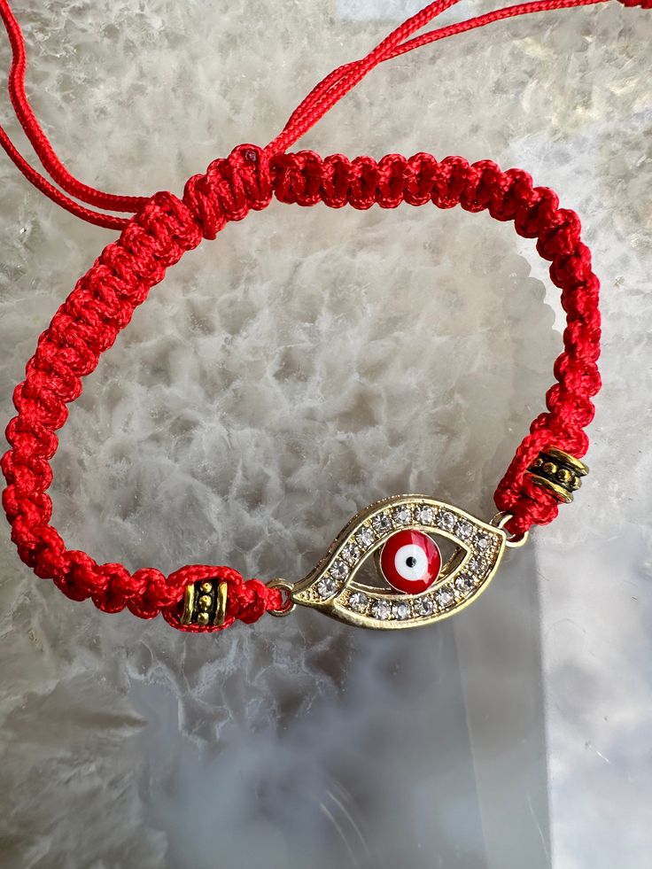 a red string bracelet with an evil eye charm