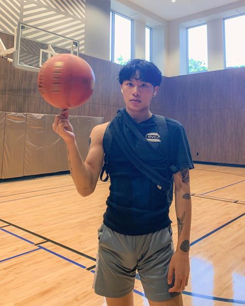 a young man holding a basketball on top of a hard wood floored gym court