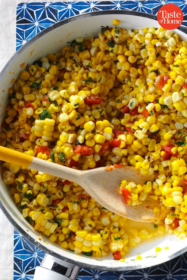 corn in a pot with a wooden spoon on the side and a blue patterned table cloth