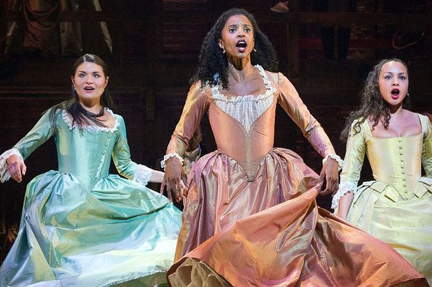 three women in dresses are performing on stage