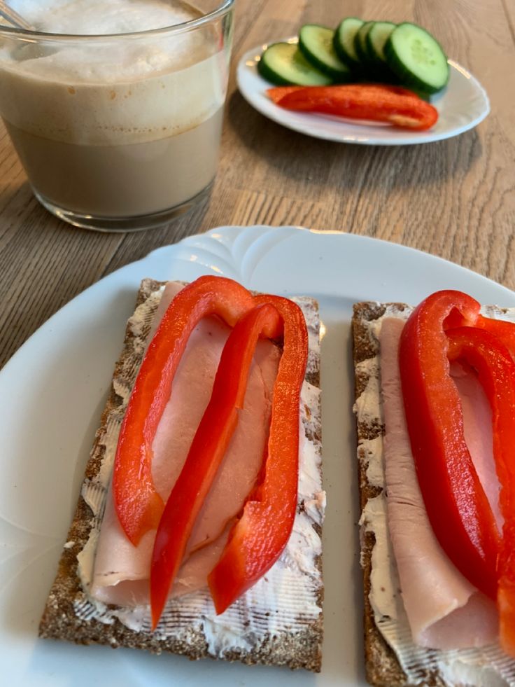 two slices of bread with meat and vegetables on them next to a glass of milk