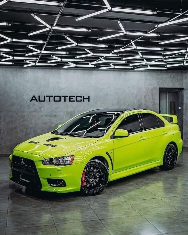 a bright yellow car is parked in front of a sign that says autotech,