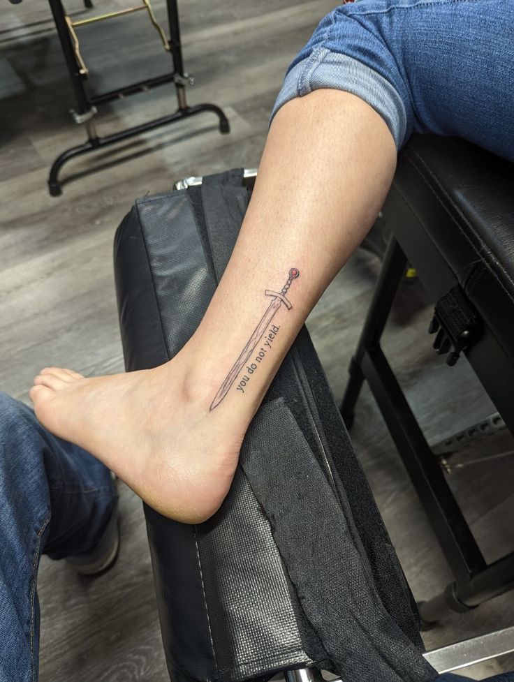 a person with a tattoo on their foot sitting next to a piece of luggage in an airport