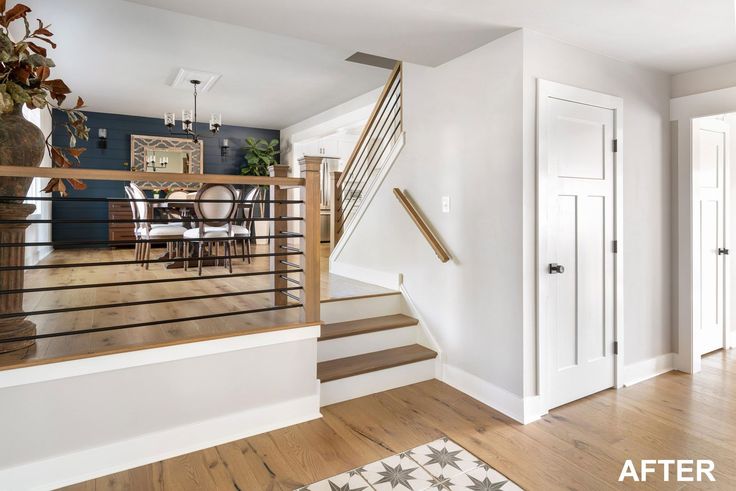 an empty living room with stairs leading up to the second floor and dining area in the background