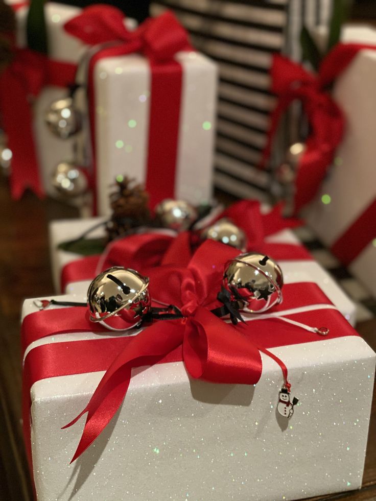 two christmas presents wrapped in red and white paper with bells on them, sitting next to each other