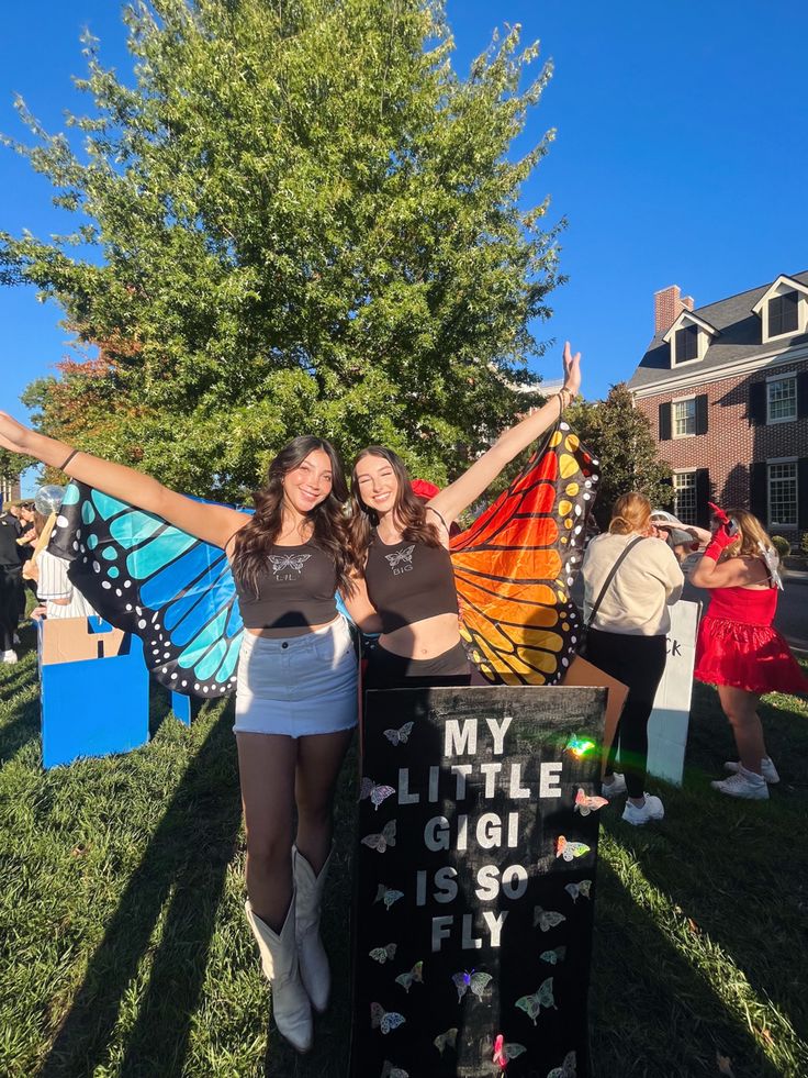 two girls standing next to each other with their arms in the air and one holding a kite