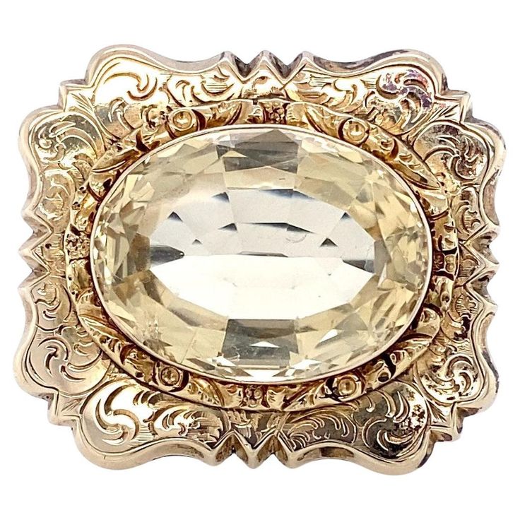 This fabulous Antique brooch with repoussé setting and scroll work in 10 karat yellow gold containing a large 15.82 carat oval citrine was created approximately in the last few decades of the 1800s, Circa 1880. There were two Gothic Revival styles in the 1800s and this is from the latter. It bears a resemblance to the mourning styles so popular in the earlier part of the 1800s during the first Gothic revival, but citrine is not a common gemstone in mourning jewelry. This strikes me as simply a fashion brooch and not necessarily a mourning brooch, but that's likely subject to interpretation as different books on the subject will state different things in reference to the gemstones used. This lovely brooch measures 1 1/4 inches long by 1 1/8 inches high. The C clasp is of the period, but has Classic Gold Intaglio Brooch, Classic Gold Brooch With Intaglio Detail, Classic Gold Intaglio Brooches, Classic Gold Brooches With Intaglio, Antique Gold Intaglio Brooches, Ornate Yellow Gold Brooch For Formal Occasions, Ornate Oval Engraved Brooches, Ornate Oval Intaglio Brooches, Antique Gold Oval Brooch