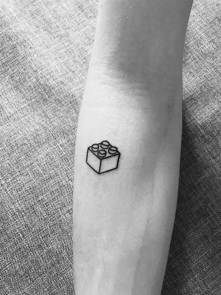 a small black and white gift box tattoo on the left inner arm