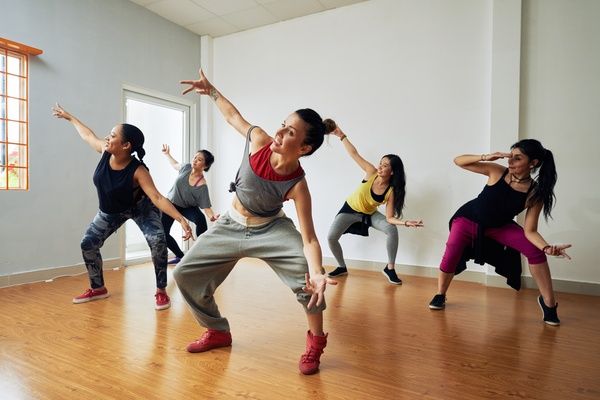 a group of people in a dance class doing various moves on the floor with their hands up